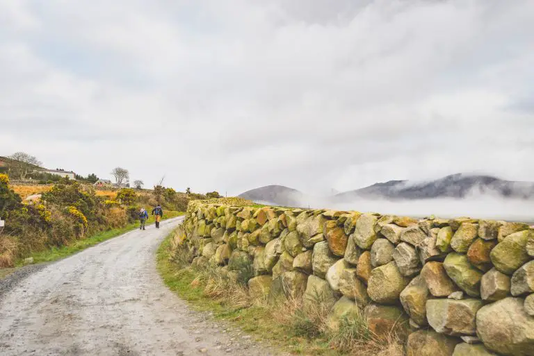 Pareja paseando por un camino rodeado de muros de piedra en Irlanda.