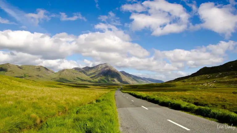 Carretera rodeada de vegetación y montañas, totalmente aislada en Irlanda.